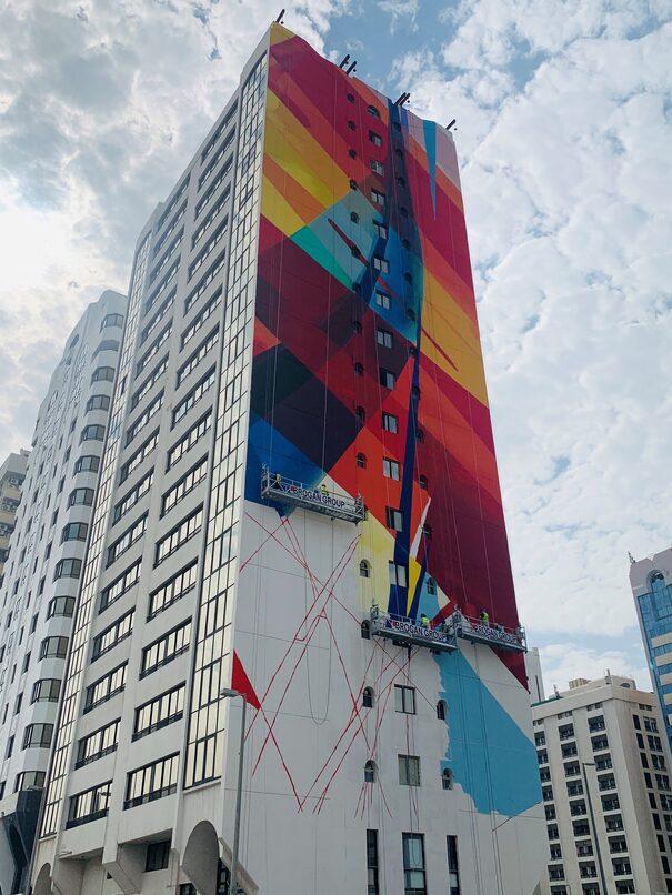 tall building with decorations on the side of it and suspended access cradles towards the bottom